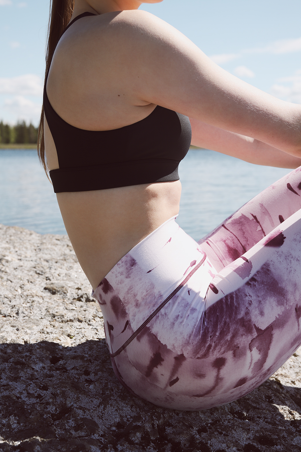 Close-up of person sitting on rocks wearing Silver birch - Soahki lily leggings with pink and purple tie-dye print by the lake